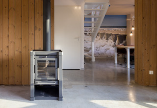 Modern living room in a beach house with stove, wood panel walls and stairs, Noordzee Resort Vlissingen, NL.