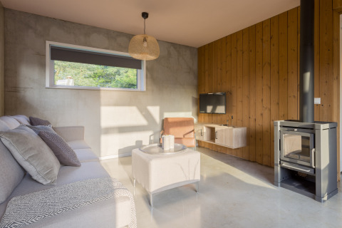 Modern living room with wood stove, sofa, and window at «Noordzee» Resort Vlissingen beach house, Netherlands.