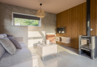 Modern living room with wood stove, sofa, and window at «Noordzee» Resort Vlissingen beach house, Netherlands.