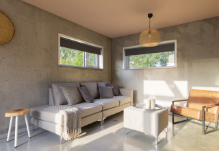 Bright modern living room in 'Noordzee' Resort Vlissingen 3 beach house, Netherlands, with sofa and chair.