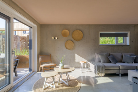 Bright living area of a beach house with modern decor, large windows, and views to the outside terrace.