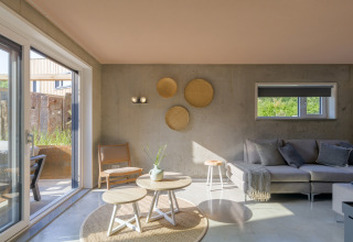 Bright living area of a beach house with modern decor, large windows, and views to the outside terrace.
