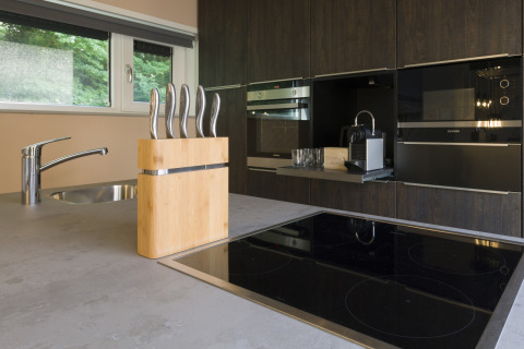 Modern kitchen at Noordzee Resort Vlissingen 3 with glass cooktop, knife block, coffee maker and window view.