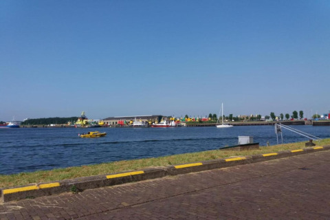 View from a beach house overlooking a harbor with boats, quay, and clear blue sky on a sunny day.