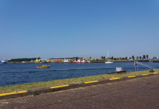 View from a beach house overlooking a harbor with boats, quay, and clear blue sky on a sunny day.
