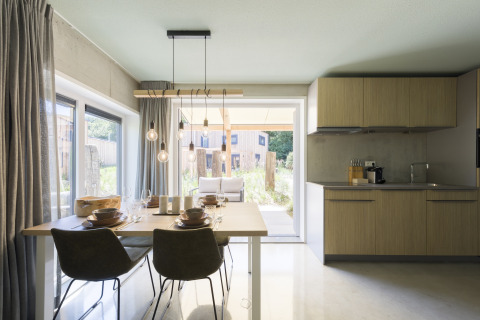 Modernes Esszimmer und Küche im Strandhaus Noordzee Resort Vlissingen in den Niederlanden, Gartenblick.