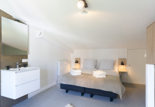 Helles Schlafzimmer mit Doppelbett und Waschbecken im Strandhaus Noordzee Resort Vlissingen 2, Niederlande.
