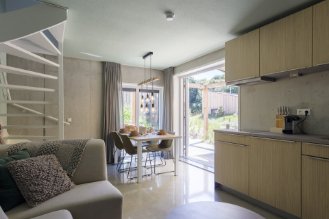 Modernes Wohn- und Esszimmer im Strandhaus «Noordzee» Resort Vlissingen 2 mit Gartenblick in Holland.