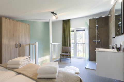 Modernes Schlafzimmer mit eigenem Bad und Dusche im Noordzee Resort Vlissingen, Niederlande.