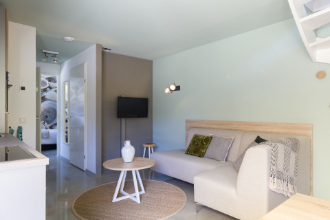 Wohnzimmer im Strandhaus Noordzee Resort Vlissingen 2, Niederlande, mit Sofa, Tisch und Dekor.