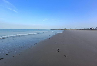 Strandansicht beim Noordzee Resort Vlissingen 2 in den Niederlanden mit ruhigem Wasser und blauem Himmel.