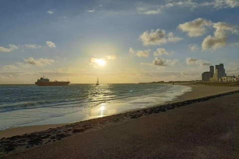 Sonnenuntergangsstrand mit Schiffen und Gebäuden bei Noordzee Resort Vlissingen 2, Niederlande.