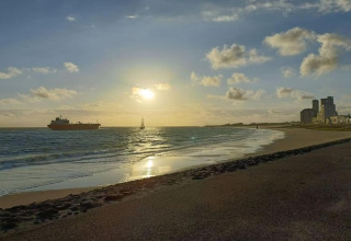 Sonnenuntergangsstrand mit Schiffen und Gebäuden bei Noordzee Resort Vlissingen 2, Niederlande.