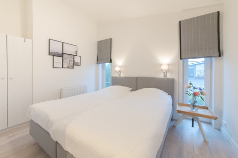 Camera da letto luminosa e moderna con due letti singoli e lampade a parete al Water Resort Oosterschelde 13.