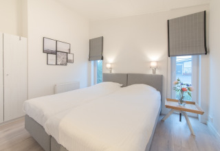 Camera da letto luminosa e moderna con due letti singoli e lampade a parete al Water Resort Oosterschelde 13.