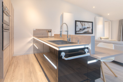 Cucina moderna lodge con mobili neri lucidi, dettagli in legno e isola al Water Resort Oosterschelde, Paesi Bassi.