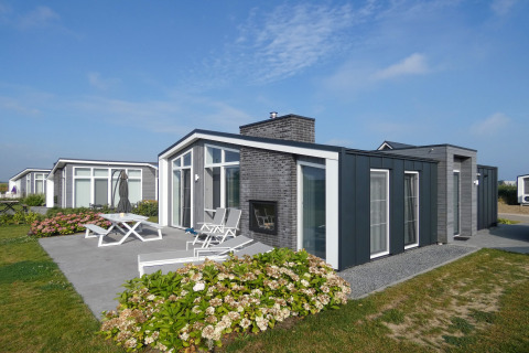 Lodge moderno al Water Resort Oosterschelde 13 nei Paesi Bassi con patio, mobili da giardino e fiori.