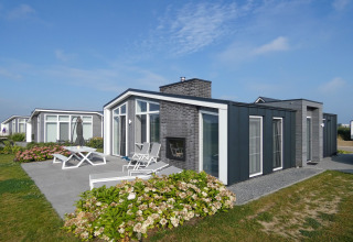 Lodge moderno al Water Resort Oosterschelde 13 nei Paesi Bassi con patio, mobili da giardino e fiori.