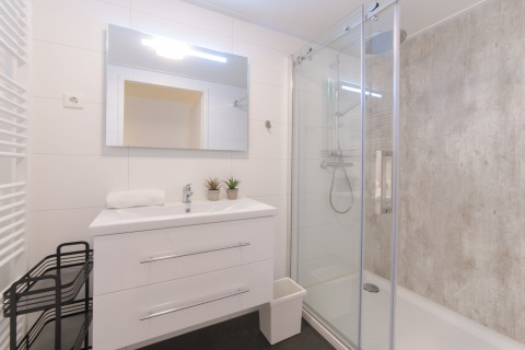 Bagno moderno al Water Resort Oosterschelde 13 con lavabo bianco, specchio grande e box doccia in vetro.