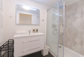 Bagno moderno al Water Resort Oosterschelde 13 con lavabo bianco, specchio grande e box doccia in vetro.