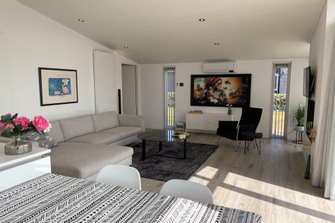 Moderne stue i Water Resort Oosterschelde 46, Holland, med sofa, spisebord og stort kunstværk.