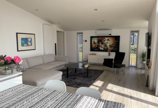 Moderne stue i Water Resort Oosterschelde 46, Holland, med sofa, spisebord og stort kunstværk.