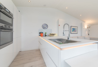 Moderne hvidt køkken med indbygget ovn, køkkenø og elegant vask, Water Resort Oosterschelde 46, Holland.