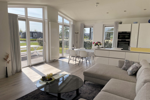 Lys og moderne opholdsstue og køkken i Water Resort Oosterschelde 46 lodge med store vinduer i Holland.