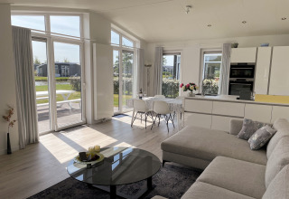 Lys og moderne opholdsstue og køkken i Water Resort Oosterschelde 46 lodge med store vinduer i Holland.