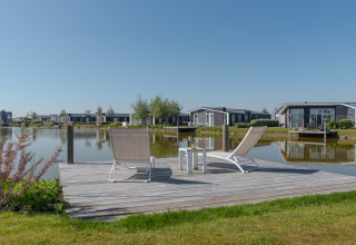 To liggestole på en træterrasse ved vandet på Water Resort Oosterschelde 46 i Holland, med moderne hytter.