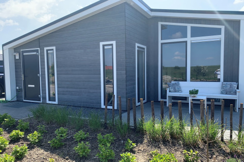 Moderne hytte ved Water Resort Oosterschelde 46 i Holland, med have, bænk og store vinduer.