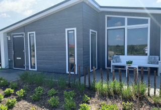 Moderne hytte ved Water Resort Oosterschelde 46 i Holland, med have, bænk og store vinduer.