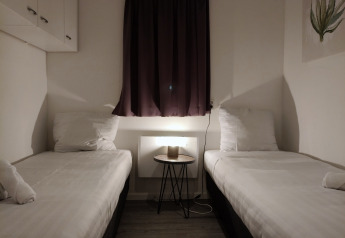 Twee eenpersoonsbedden in een eenvoudige kamer in Hackfort-lodge, Kaatsheuvel, Nederland, met nachtkastje.