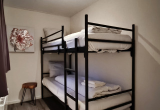 Modern lodge room in Hackfort, Kaatsheuvel, featuring a bunk bed, artwork, stool, and natural light.