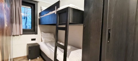 Cozy room at Hackfort lodge in Kaatsheuvel, Netherlands, with bunk bed, dark wardrobe and a small window.
