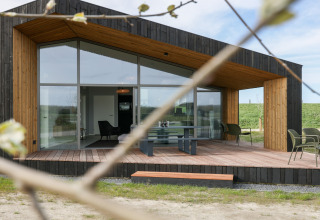 Moderne lodge med store glasfacader og træterrasse på Heerlijkheid Vlietenburg 1 i Holland, set udefra.