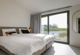 Moderne lodge soveværelse med dobbeltseng, stort vindue og udsigt, Heerlijkheid Vlietenburg 1, Holland.