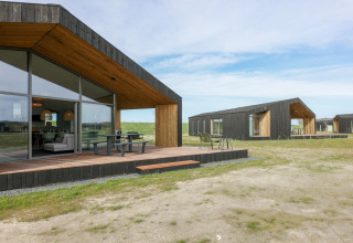 Moderne lodges på Heerlijkheid Vlietenburg 1 i Holland, med store vinduer og trædæk i naturlige omgivelser.