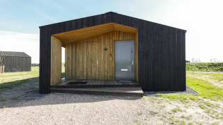 Moderne træhytte ved Heerlijkheid Vlietenburg 1, sort facade og veranda, placeret i naturskønt område.
