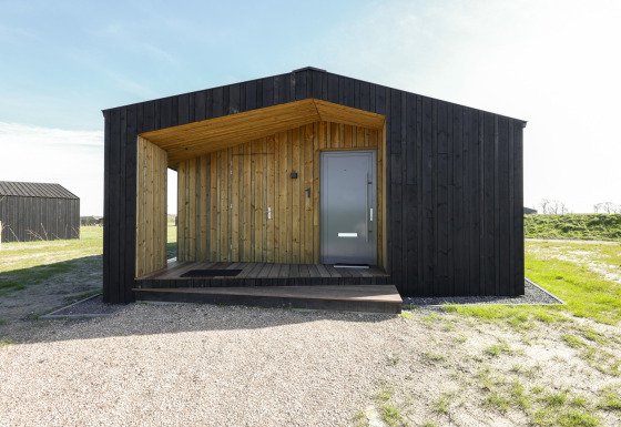 Moderne træhytte ved Heerlijkheid Vlietenburg 1, sort facade og veranda, placeret i naturskønt område.