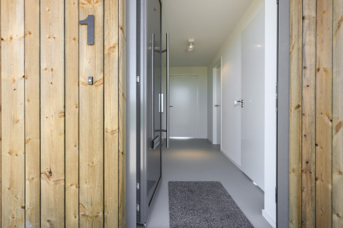Indgang til Heerlijkheid Vlietenburg 1 lodge i Holland med trævægge, tæppe og moderne interiør.