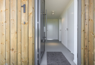 Indgang til Heerlijkheid Vlietenburg 1 lodge i Holland med trævægge, tæppe og moderne interiør.