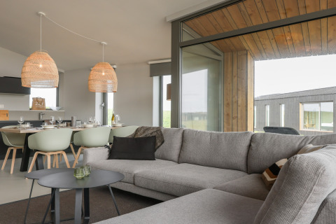 Stue i Heerlijkheid Vlietenburg 1-lodge i Holland, moderne sofa, spisebord og store vinduer.