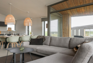 Stue i Heerlijkheid Vlietenburg 1-lodge i Holland, moderne sofa, spisebord og store vinduer.