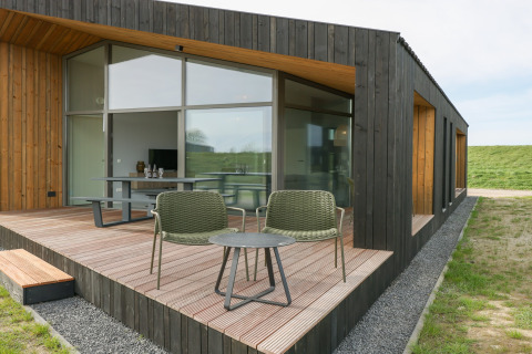 Moderne lodge med træterrasse, store vinduer og udendørs siddepladser ved Heerlijkheid Vlietenburg 1.