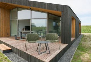 Moderne lodge med træterrasse, store vinduer og udendørs siddepladser ved Heerlijkheid Vlietenburg 1.