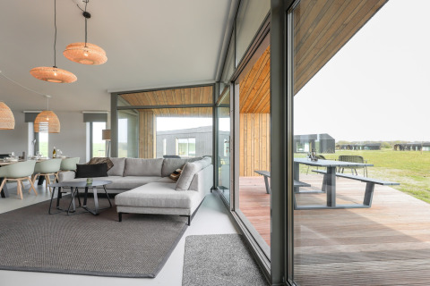 Moderne opholdsstue i Heerlijkheid Vlietenburg 1 med store vinduer og udsigt til en træterrasse i Holland.