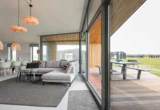 Moderne opholdsstue i Heerlijkheid Vlietenburg 1 med store vinduer og udsigt til en træterrasse i Holland.