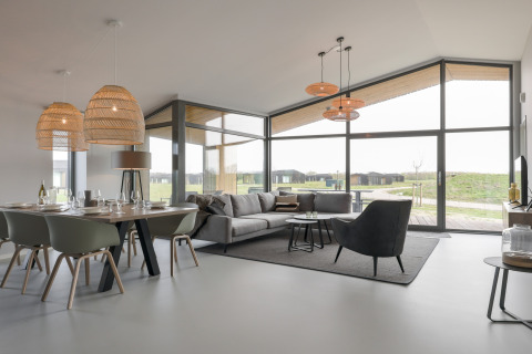 Moderne og rummelig stue og spisestue i Heerlijkheid Vlietenburg 1-lodge i Holland med store vinduer.