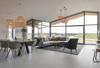 Moderne og rummelig stue og spisestue i Heerlijkheid Vlietenburg 1-lodge i Holland med store vinduer.